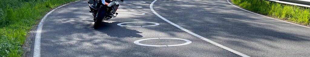 Motorradfahrer umfährt in der Kurve die ellipsenförmigen Markierungen.