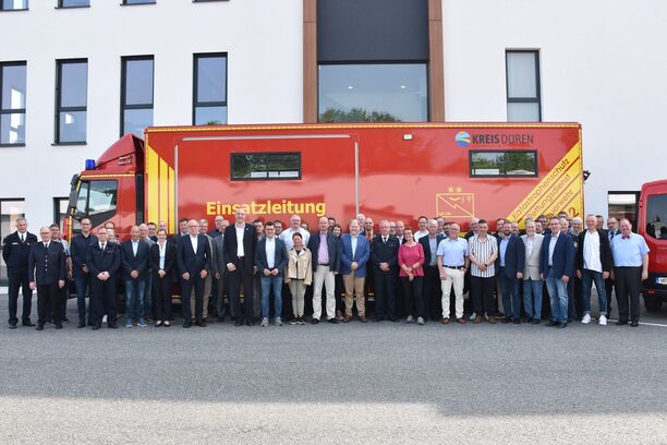 Bild zeigt ein Einsatzfahrzeug und alle Teilnehmerinnen und Teilnehmer des ersten Symposiums Katastrophenschutz im Kreis Düren.