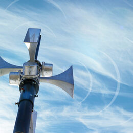 Outdoor loudspeaker against the background of blue sky, sound waves.