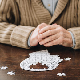 cropped view of senior man playing with puzzles on table