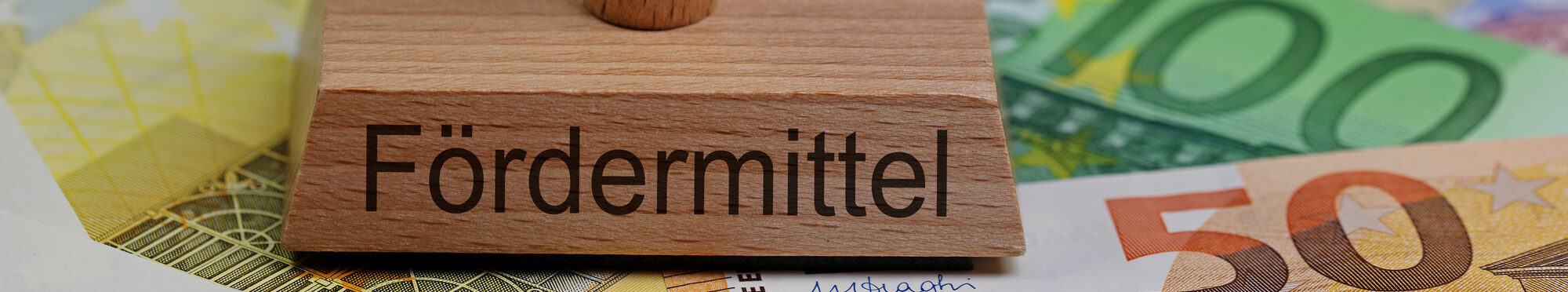 Stempel mit der Aufschrift "Fördermittel" auf Geldscheinen