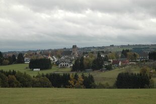 Blick auf das Dorf Vossenack. Zu sehen sind viele Bäume, grüne Wiesen und ein paar Häuser.
