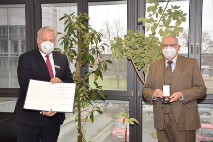 Landrat Wolfgang Spelthahn steht links mit einer Urkunde in der Hand. Neben ihm ist Dr. Reinhard Odoj, der die Urkunde erhält.