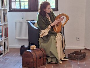 Frau mit Instrument auf Stuhl.