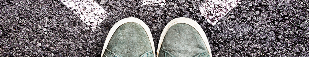 Schuhe auf Straße mit verschiedenen Pfeilen in unterschiedliche Richtung.