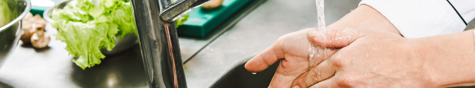 cropped view of female chef washing hands over sink in restaurant kitchen