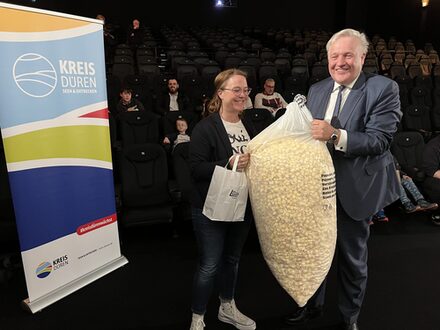 Das Bild zeigt den Landrat und eine Frau mit einem großen Sack Popcorn.