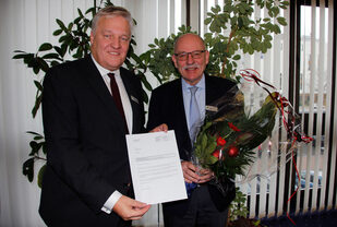 Landrat Wolfgang Spelthahn (l.) überreichte seinem neuen Allgemeinen Vertreter Peter Kaptain das Ernennungsschreiben und einen Strauß Blumen.
