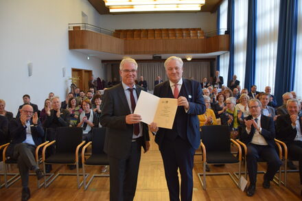 Hans Martin Steins und Landrat Wolfgang Spelthahn bei der Urkundenübergabe vor den Anwesenden.