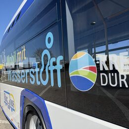 Zu sehen isst ein Wasserstoffbus von der Seite mit der Aufschrift "mobil mit Wasserstoff" und Kreis Düren