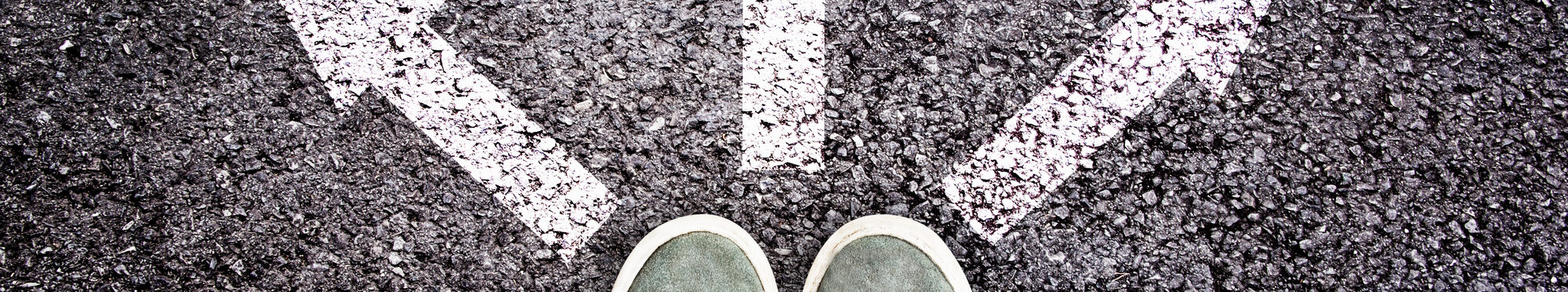 Shoes and arrows pointing in different directions on asphalt floor