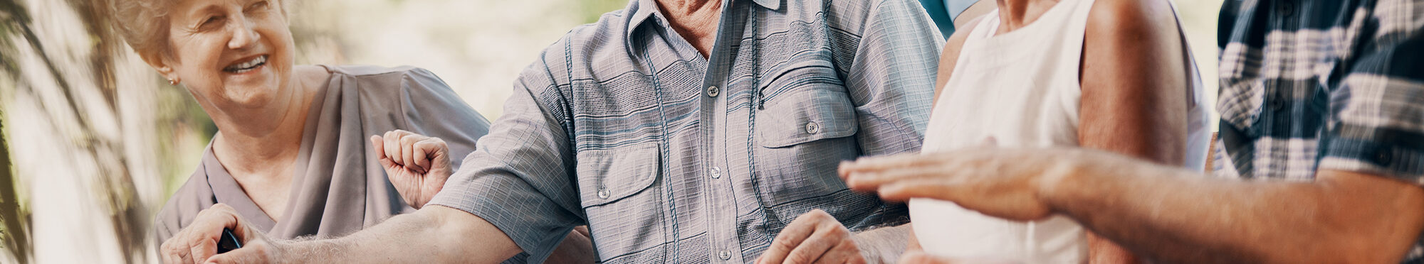 Happy elderly man with walking stick and smiling senior people relaxing in the garden